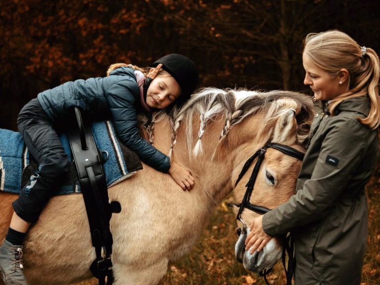 Reittherapie Ivenack Ein Kind lehnt über einem Pferdehals und ist glücklich.